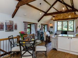 une cuisine avec des armoires blanches et une table avec des chaises dans l'établissement Stable Cottage, à Uley