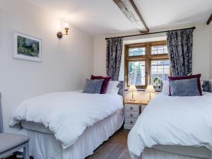 deux lits dans une chambre avec une fenêtre dans l'établissement Stable Cottage, à Uley
