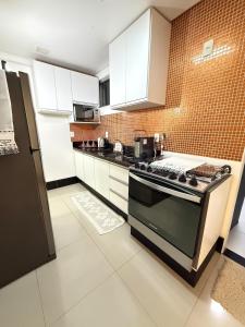 a kitchen with white cabinets and a stove top oven at Casa completa e climatizada em Ilhéus in Ilhéus