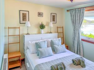 Un dormitorio con una cama blanca con una ventana. en The Heron, en Ardentinny