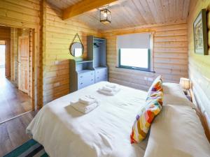 Un dormitorio con una cama grande en una cabaña de madera. en Bluebell Lodge - Uk50875, en Hittisleigh 6 fotos más