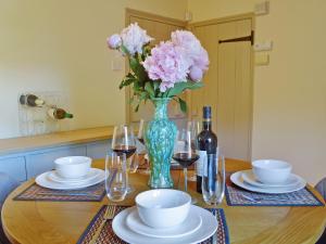 a table with a vase of pink flowers and wine glasses at Owl Cottage in Fordwich