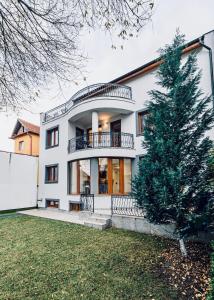 a white house with a tree in front of it at Vila LINA in Braşov