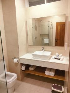 Un baño con lavabo, inodoro y espejo. en Bamburi Beach Hotel, en Bamburi