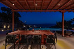 Elit Villa Psarou في بسارو: طاولة وكراسي خشبية على فناء في الليل