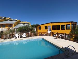 a swimming pool with a yellow house in the background at Complejo EL ALTO in Tanti
