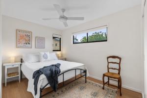 une chambre avec un lit et une chaise dans l'établissement Coastal Retreat, à Kioloa