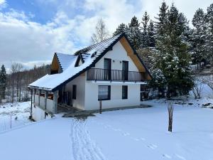 a house in the snow with footprints in the yard at Domki przy szlaku Szczebel in Lubień