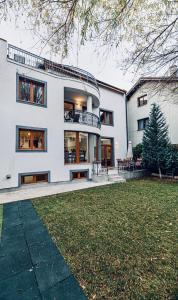 a large white house with a lawn in front of it at Vila LINA in Braşov