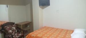 una camera con letto, sedia e TV di Hospedaje El Encanto a Huancayo