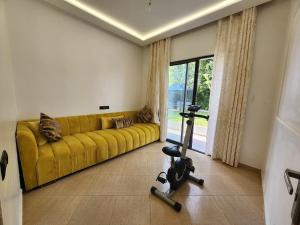 a living room with a yellow couch and a treadmill at Villa Luxe Fès avec Piscine & Spa, proche aéroport, Private Hammam in Fès