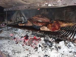 a turkey and meat cooking on a grill at Complejo EL ALTO in Tanti