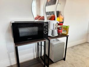 a microwave on a stand next to a wall at Lovely 1-Bed City Centre escape with Kitchen & Free Parking in Spon End