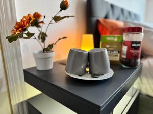 a black table with two cups and a vase with flowers at Lovely 1-Bed City Centre escape with Kitchen & Free Parking in Spon End +1 photo