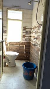 a bathroom with a toilet and a window and a bucket at Modern Guest House in Ujjain +10 photos