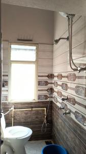 a bathroom with a toilet and a window at Modern Guest House in Ujjain