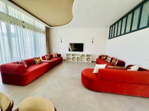 uma sala de estar com dois sofás vermelhos e uma televisão em Modern villa with a private pool em Marraquexe