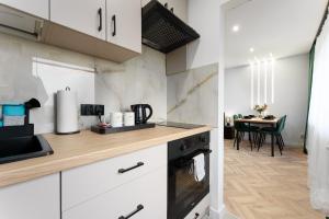 a kitchen with white cabinets and a dining room with a table at Modern Home in Sosnowiec