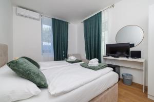 two beds in a room with green curtains and a tv at Beach Villa Selce in Selce