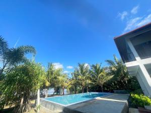 une piscine devant un immeuble avec des palmiers dans l'établissement Ashansa Lagoon Resort, à Tangalle