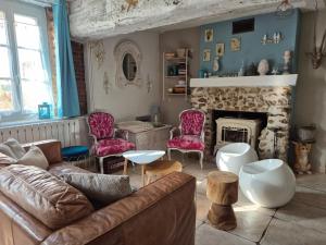 ein Wohnzimmer mit Couch und Kamin in der Unterkunft Maison féérique et ludique, avec jeux de piste in Saint-Romain-le-Preux