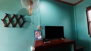a room with a desk with a television and a fan at Saran Resort room 9 in Ban Khok Wat