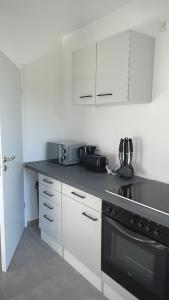 La cuisine est équipée de placards blancs et d'un four avec plaques de cuisson noires. dans l'établissement Frisch saniert, Moderne Ferienwohnungen für 1 bis 37 Personen, Warme Weihnachten, à Böbingen an der Rems