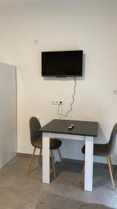 une table avec deux chaises et une télévision murale dans l'établissement Frisch saniert, Moderne Ferienwohnungen für 1 bis 37 Personen, Warme Weihnachten, à Böbingen an der Rems