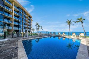 a resort swimming pool with palm trees and the ocean at Kihei Surfside 306 · KSS 306 Updated BeachFront 1BD w Ocean View in Wailea