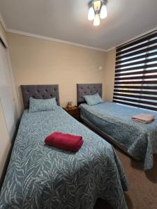 1 Schlafzimmer mit 2 Betten und einem roten Kissen auf dem Bett in der Unterkunft Fabuloso Amplio Departamento 3 dorm Parcking y Wifi in Rancagua + 17 Fotos