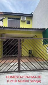 une maison jaune avec une terrasse en bois devant elle dans l'établissement Homestay RAHMAJID, à Segamat 5 autres photos