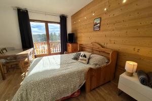 ein Schlafzimmer mit einem Bett und einer Holzwand in der Unterkunft Chaleureux studio au pied des pistes - Le refuge in Les Déserts