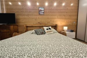 ein Schlafzimmer mit einem Bett mit einer Holzwand in der Unterkunft Chaleureux studio au pied des pistes - Le refuge in Les Déserts + 30 Fotos