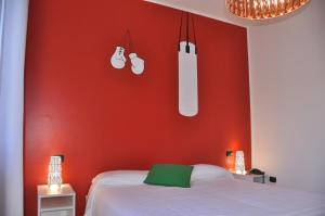a bedroom with a red wall with a bed and two lights at Lo Scoiattolo Piedmont Bike Hotel in Pralormo