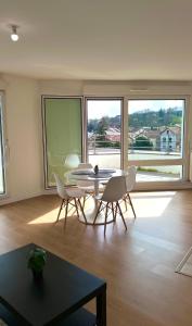 ein Esszimmer mit Tisch und Stühlen und einem großen Fenster in der Unterkunft Charme Citadin in Villemomble