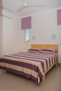 1 dormitorio con 1 cama grande con manta a rayas en Villa Alexis - Location de vacances à Trou aux Biches, en Trou aux Biches