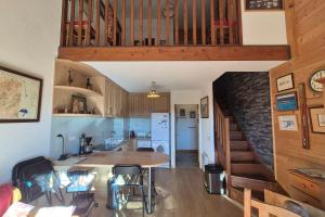eine Küche und ein Wohnzimmer mit einem Tisch und einer Treppe in der Unterkunft Appartement familial au Revard vue sur le jardin d'enfant et pistes in Les Déserts