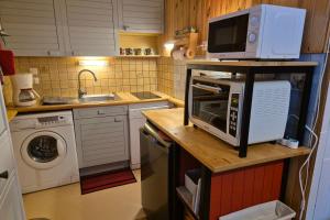 eine kleine Küche mit Mikrowelle und Spüle in der Unterkunft Appartement idéal famille - pied des pistes in Les Déserts