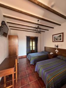 a bedroom with two beds and a table and a desk at Posada de Jose Mª El Tempranillo in Alameda