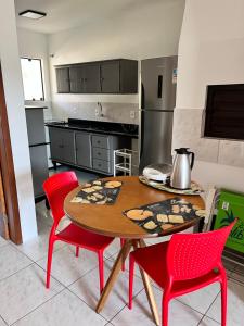 eine Küche mit einem Holztisch und roten Stühlen in der Unterkunft Residencial COLIBRI in Garopaba + 46 Fotos