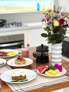 une table avec des assiettes de nourriture et un vase de fleurs dans l'établissement Villa Vana, Sitara Villa Group, à Seminyak