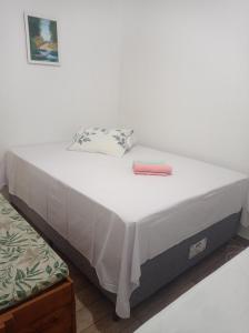a white bed with a pink box on top of it at Casa aconchegante - Morada do Sol in Piranhas