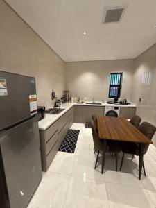 a large kitchen with a wooden table and a refrigerator at شقة البدر in Medina +16 photos
