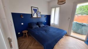 una habitación azul con una cama con una manta azul en La Maison Des Pins, en Le Mans