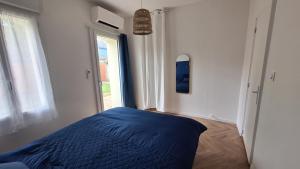 Un dormitorio con una cama azul y una ventana. en La Maison Des Pins, en Le Mans 2 fotos más