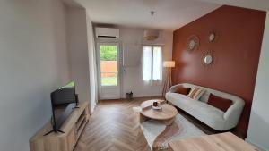 Una sala de estar con un sofá y un televisor. en La Maison Des Pins, en Le Mans