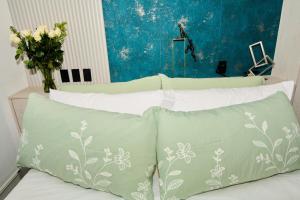 基多Studio Harmony in La Carolina and Wet Areas的一张配有绿色和白色枕头的床和一瓶鲜花 更多27张照片