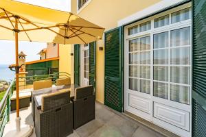 a patio with a table and chairs and an umbrella at JPL - Preces Residential in Câmara de Lobos
