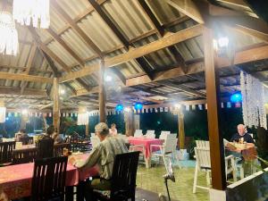 a group of people sitting at tables in a restaurant at Lucky Resort in Ko Phayam