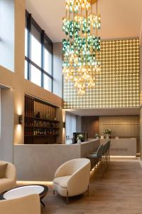 a lobby with a bar and a chandelier at Hôtel des Innovations in Marly